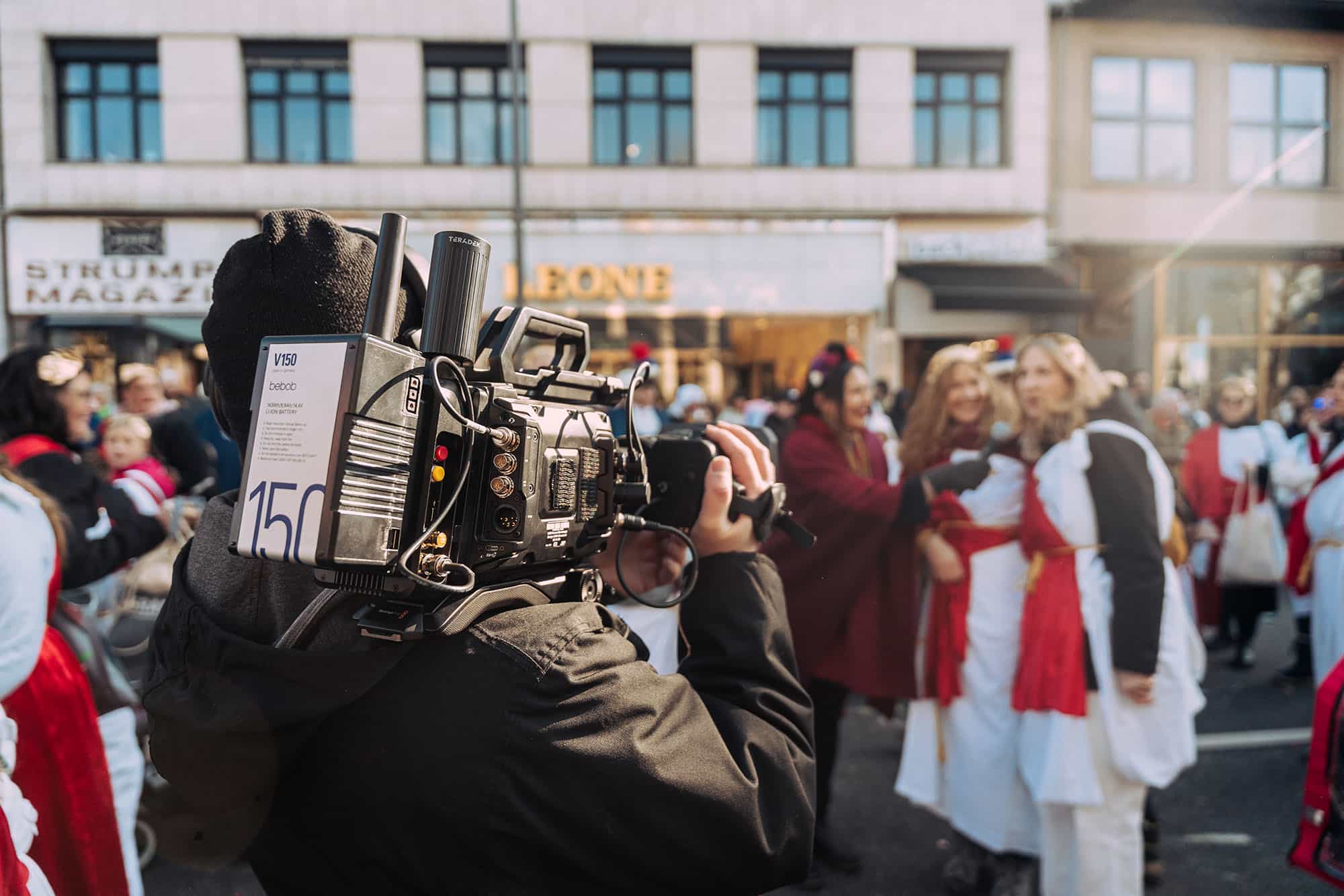 Kameramann mit einer Drahlos-Kamera auf einer Straße bei einem Karnevalsumzug.